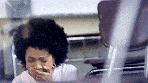 a woman covering her mouth with her hand while sitting at a desk