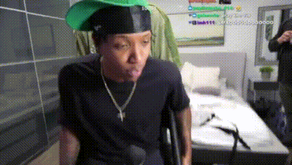 a man wearing a green hat and a black shirt is sticking out his tongue .
