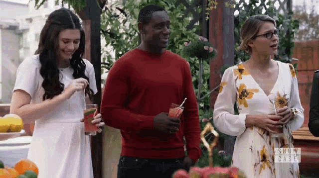 a group of people are standing next to each other holding drinks and smiling .