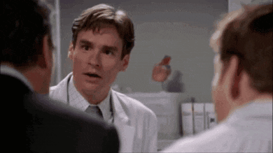 a man in a white coat and tie is talking to two other men in a room .