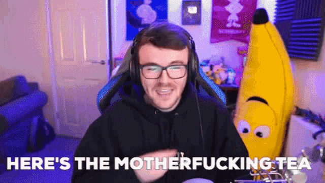 a man wearing headphones is sitting in front of a stuffed banana and says here 's the motherfucking tea