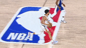 a basketball player dribbles the ball in front of a nba logo