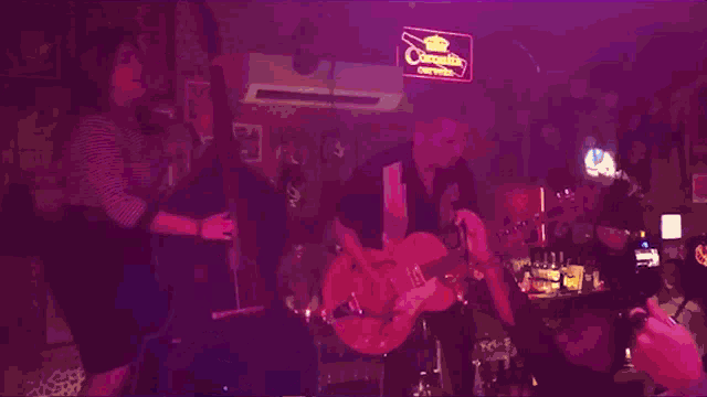 a man and a woman are playing guitars in front of a crowd in a dark room .