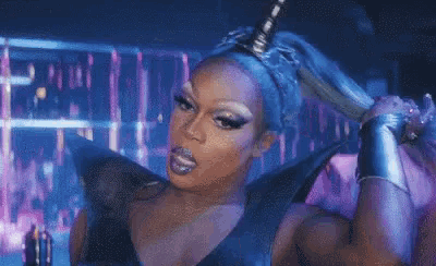 a drag queen is holding a large sword in her hand .