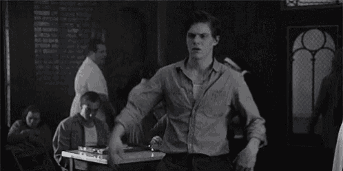 a black and white photo of a man and a woman fighting each other in a room .