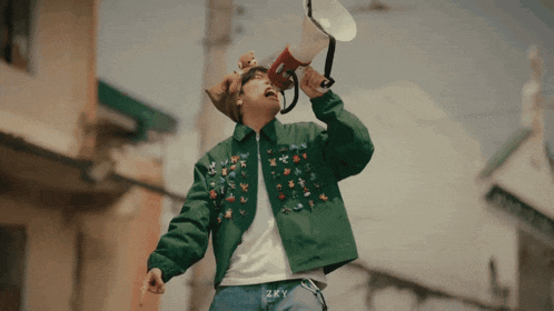 a man in a green jacket is holding a megaphone in his mouth