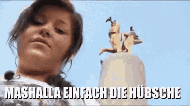 a girl is standing in front of a statue with the words mashalla einfach die hubsche written below her