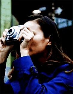 a woman in a blue coat is taking a picture with her camera