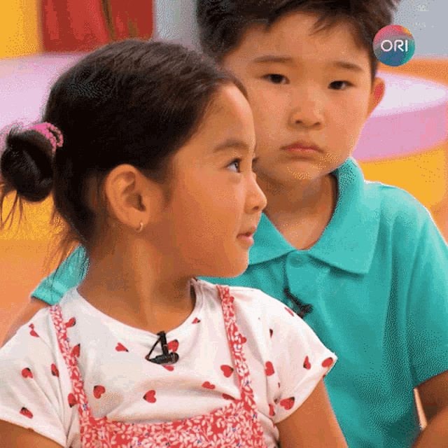 a boy and a girl are sitting next to each other and the girl is wearing a white shirt with strawberries on it