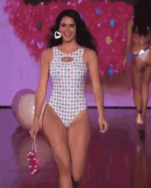 a woman in a bathing suit is walking down the runway