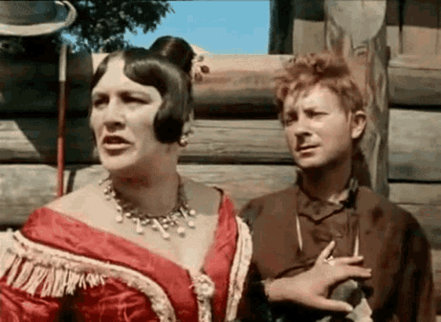 a man and a woman are standing next to each other . the woman is wearing a red dress .