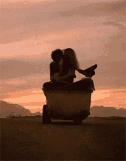 a man and a woman are kissing while sitting on a trash can .