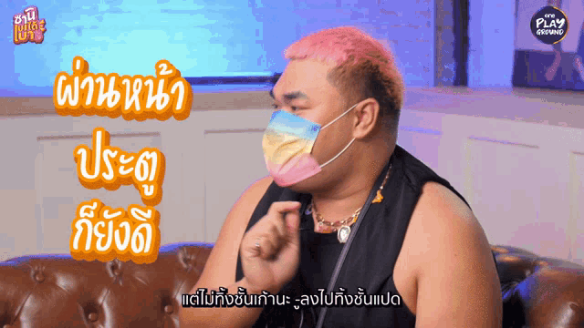 a man wearing a face mask is sitting on a couch in front of a play advertisement
