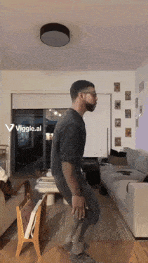 a man is dancing in a living room with a viggle.ai displayed
