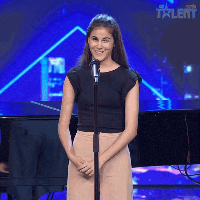 a woman stands in front of a microphone with the word talent on the bottom right