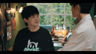 a boy wearing a black shirt that says " arcade " talks to another boy