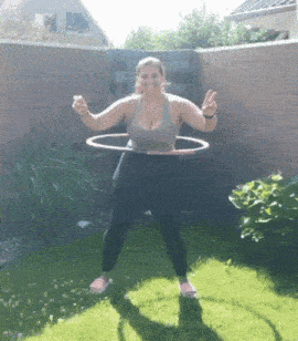 a woman is playing with a hula hoop in a garden