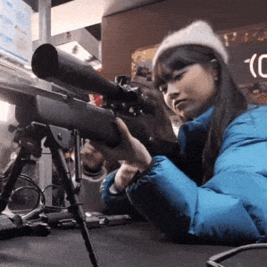a girl in a blue jacket is holding a rifle