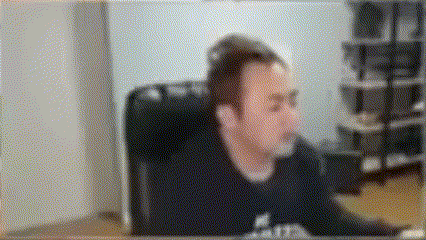 a blurry picture of a man sitting at a desk in front of a computer screen .