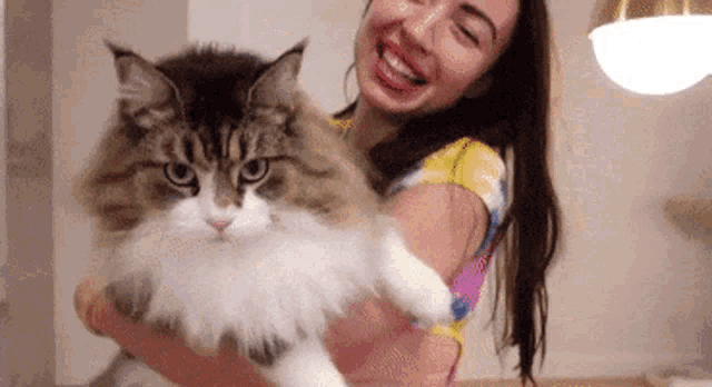 a woman is holding a cat in her arms .