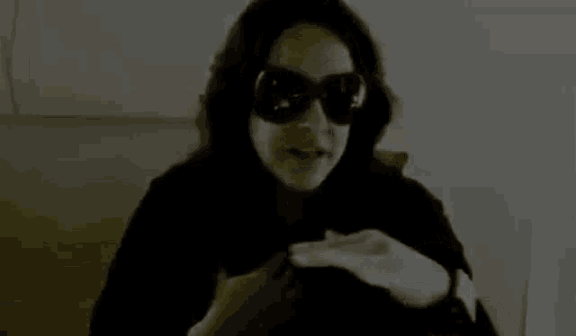 a black and white photo of a woman wearing sunglasses and a black coat .