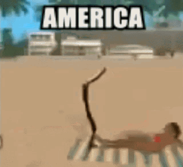 a person is laying on a striped towel on a beach under a sign that says ' america ' .