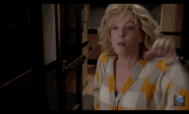 a woman in a yellow and white plaid sweater is making a funny face