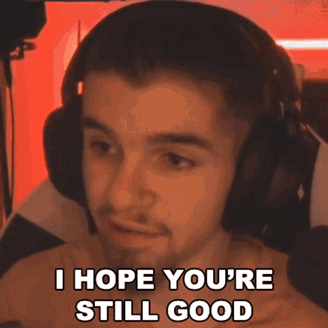 a man wearing headphones is saying `` i hope you 're still good '' while sitting in front of a computer .