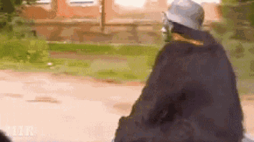 a man in a hat is riding a motorcycle on a dirt road .