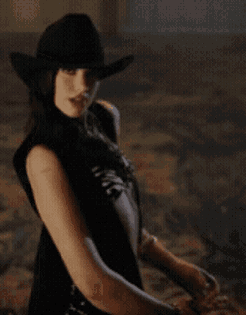 a woman wearing a black hat and a black dress is looking over her shoulder