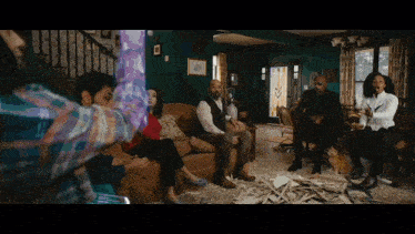 a group of people are sitting in a living room and one of them is holding a purple object in his hand