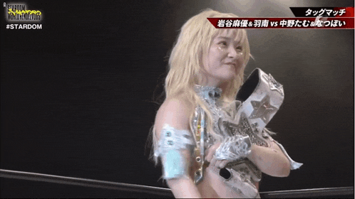 a female wrestler is holding a trophy in front of a screen that says stardom
