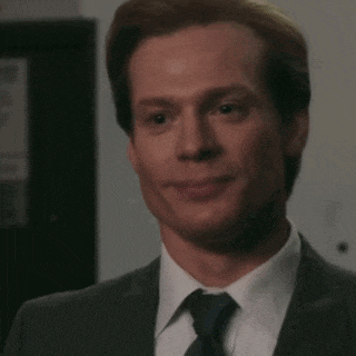 a man in a suit and tie is smiling while looking at the camera .