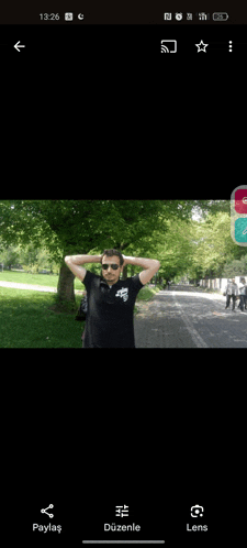 a man wearing sunglasses is standing on a sidewalk with his hands on his head