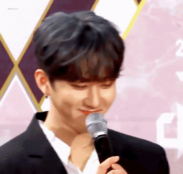 a young man in a suit is holding a microphone and smiling .