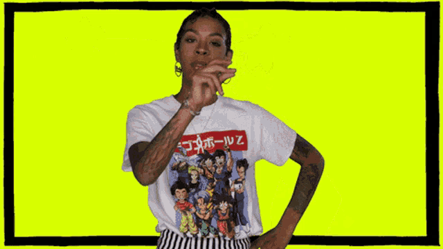 a woman wearing a dragon ball z t-shirt stands in front of a yellow background