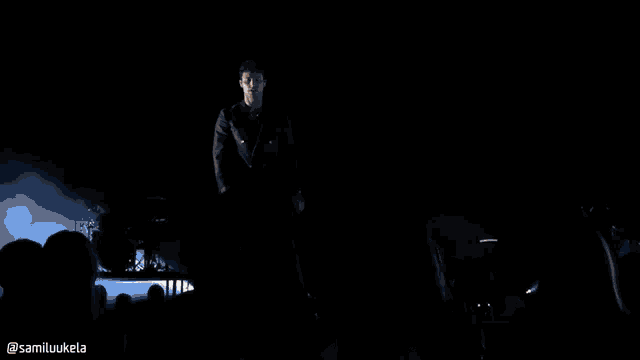 a silhouette of a group of people on a stage with a white screen in the background