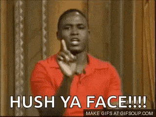a man in a red shirt is making a funny face and pointing at the camera .