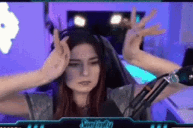 a woman wearing headphones and a microphone is making a funny face .