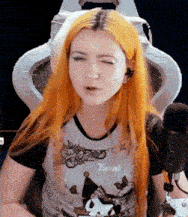 a girl with orange hair is sitting in front of a microphone and making a funny face .