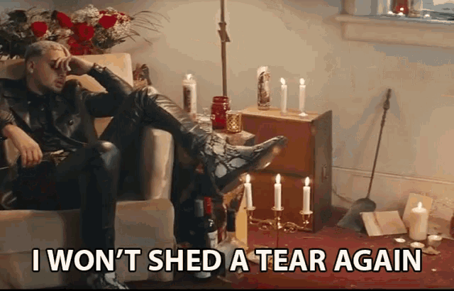 a man sits in a chair with candles and the words i won 't shed a tear again