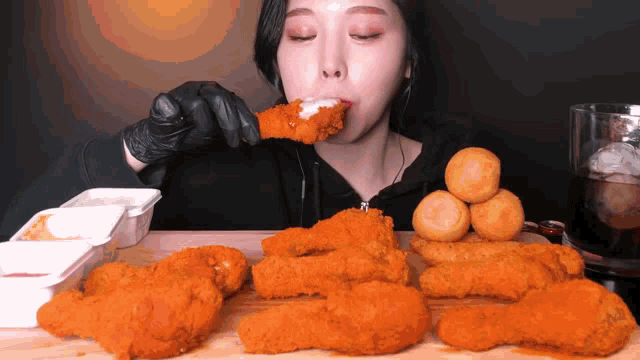 a woman in black gloves is eating fried food