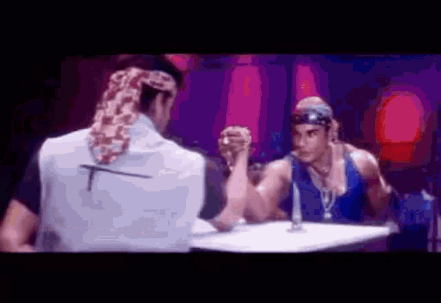 two men are arm wrestling each other in a dark room .