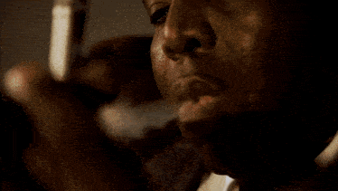 a man in a suit and tie is blowing smoke out of his mouth