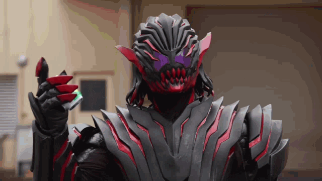 a man in a black and red costume is holding something in his hand