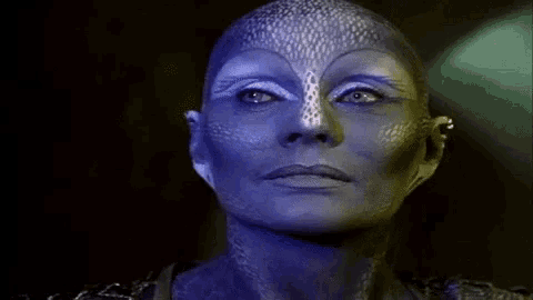 a close up of a woman 's face with blue paint on it in a dark room .