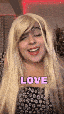 a woman wearing a blonde wig and a black and white dress with the word love on her chest