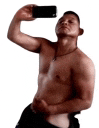 a shirtless man is taking a picture of himself with his cell phone .