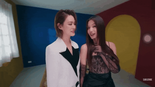 two women standing next to each other in a room with the words subscribe on the bottom