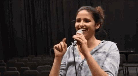 a woman singing into a microphone with a black background